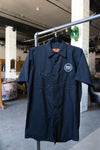 Photo of a black "work shirt." A collared, short-sleeve, button-up shirt, with the BNA logo on the left chest. 